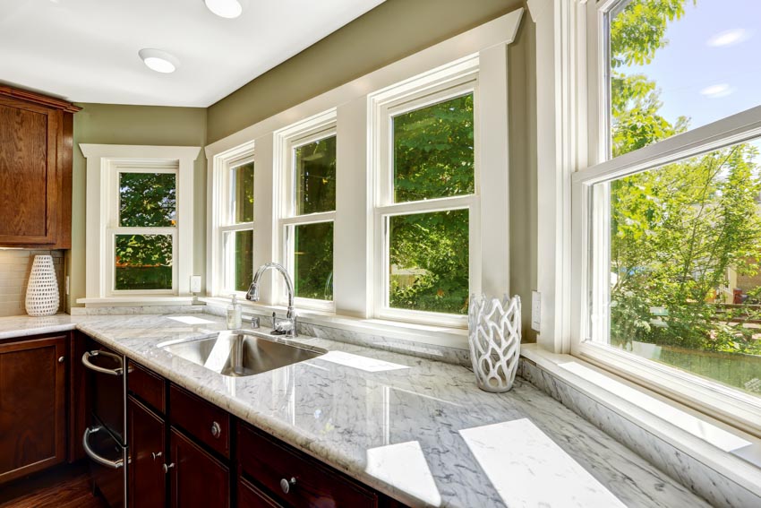 Kitchen with countertop, bay window, brown cabinets, sink, and faucet