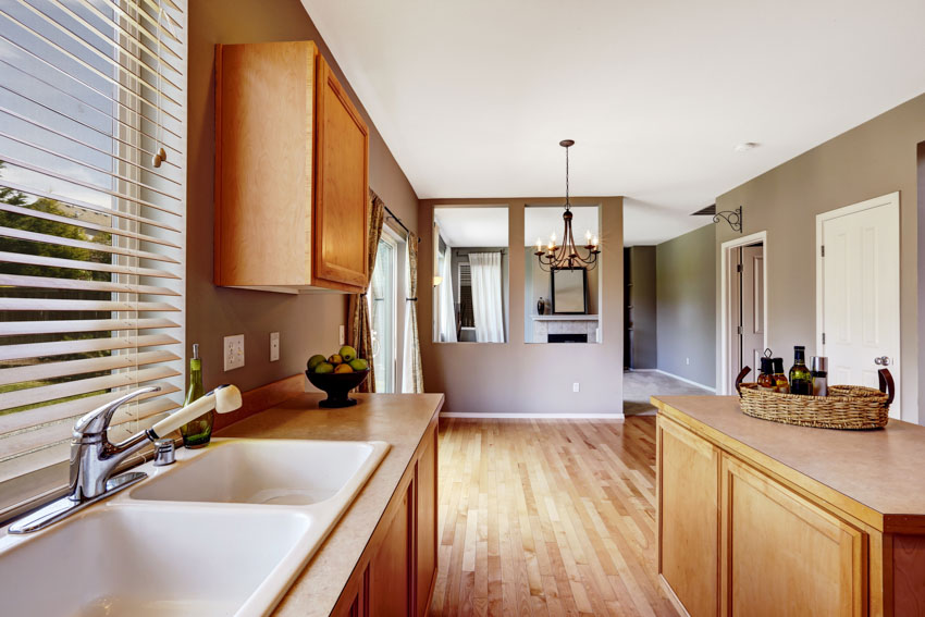 Kitchen with countertops that look like wood, sink, windows, cabinets island, and wooden flooring