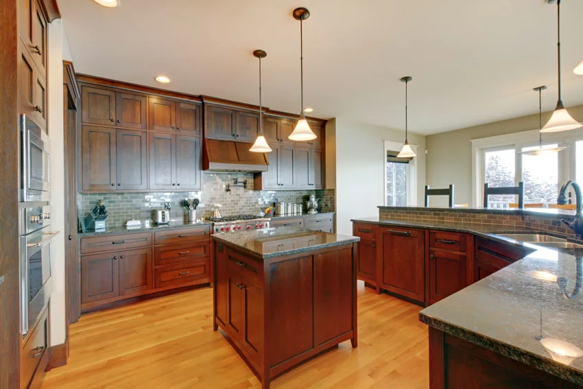 Kitchen with stained cabinets, wood floor, center island, countertops, and pendant lights