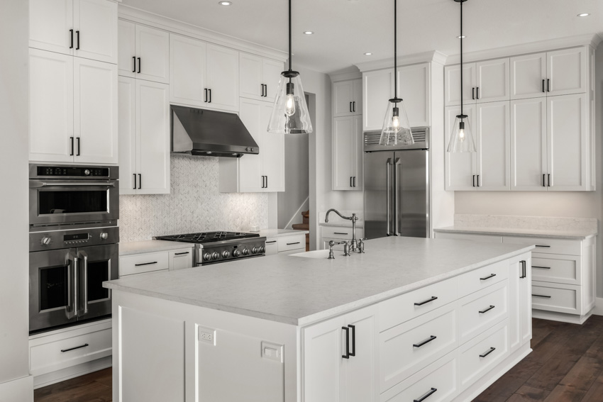 Kitchen with white shaker cabinets, center island, countertop, oven, stove, range hood, and pendant lights