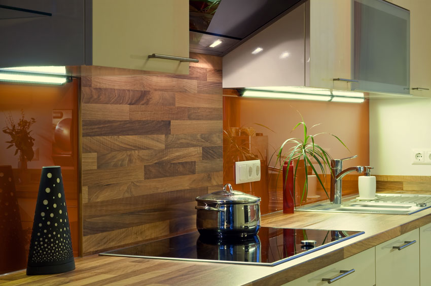Kitchen with wood countertop, wood tile backsplash, cabinets, and induction stove