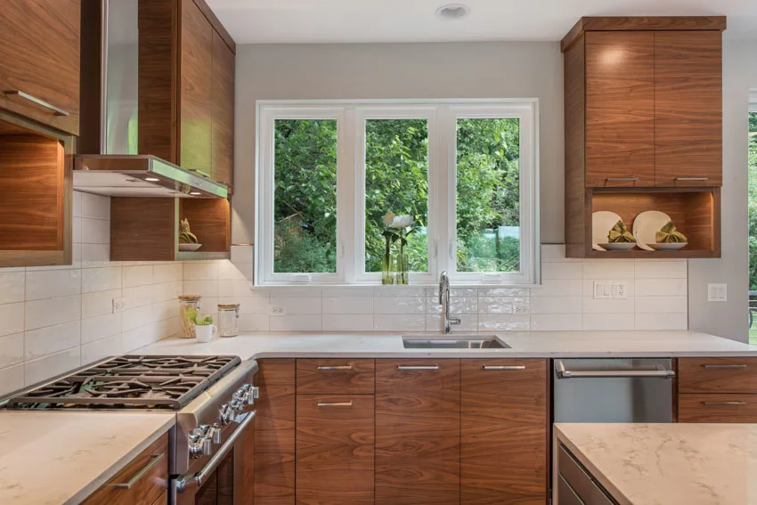 Kitchen with wood horizontal grain cabinets, backsplash, windows countertop, range hood, and stove