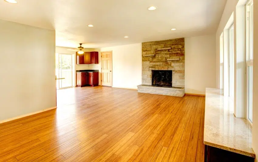 Large empty room withstone clad fireplace and recessed lighting