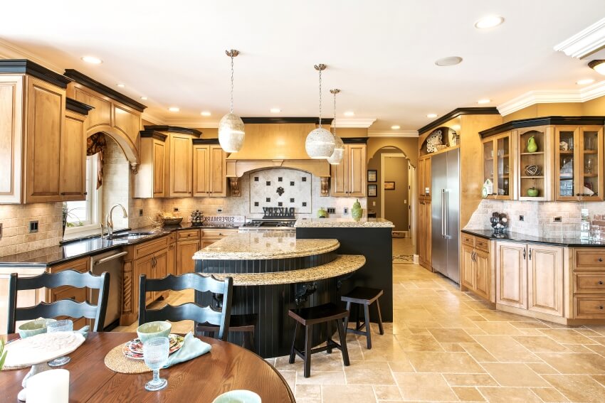 Large kitchen with pendant lights, brick backsplash, and black island with granite countertops