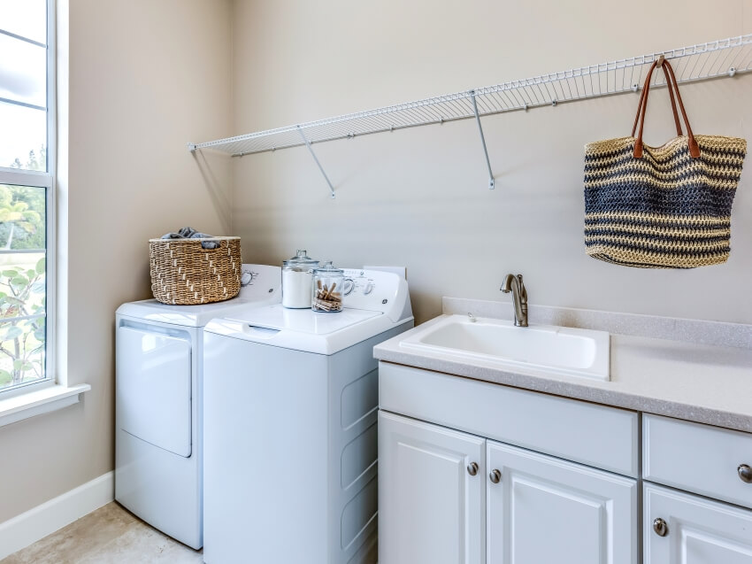 Laundry room with long metal shelf, utility sink, and white laundry machine
