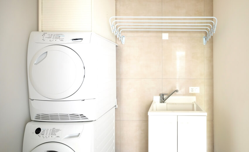 Room with undermount sink, wall mounted clothes drying rack, and washer and dryer