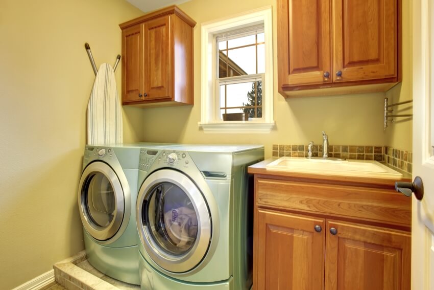 Green colored dryer and washer with tucked ironing board