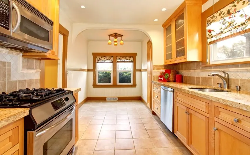 Light brown toned kitchen with white ceiling, arched doorway and wood cabinets