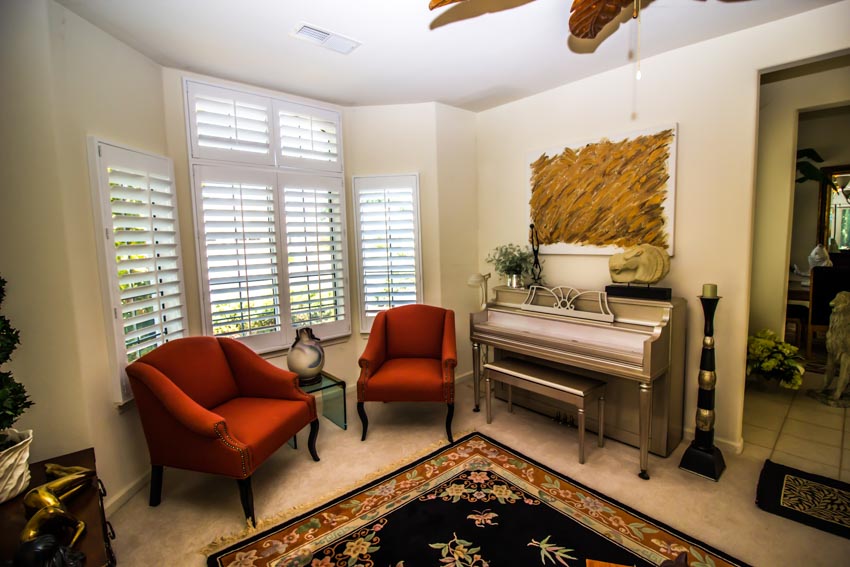 Window with blinds, piano and red chairs