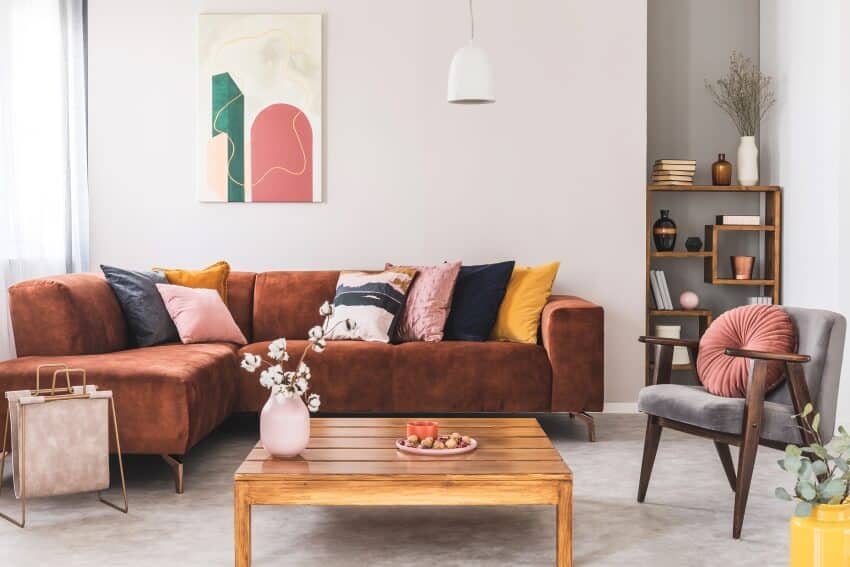 Brown corner sofa with pillows, and abstract painting on off-white wall