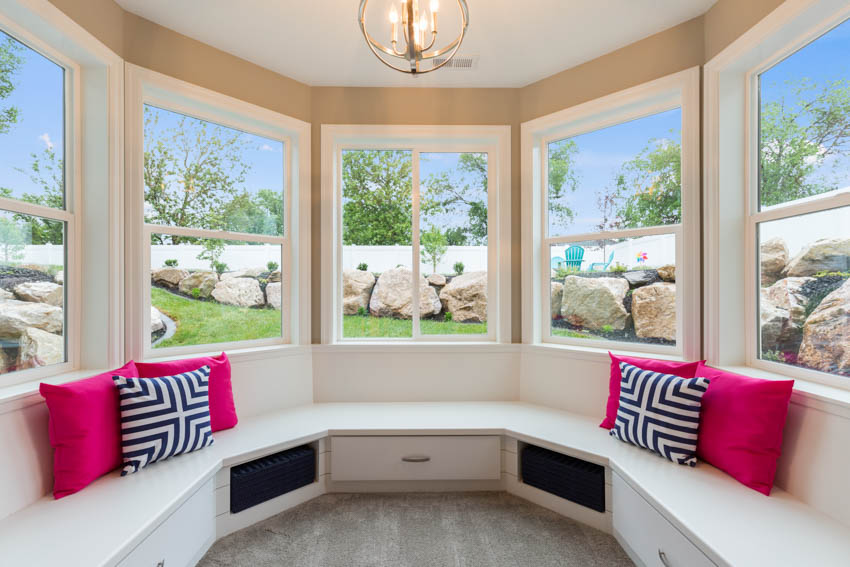 Room with bright pink pillows, printed cushions, and bulb chandelier