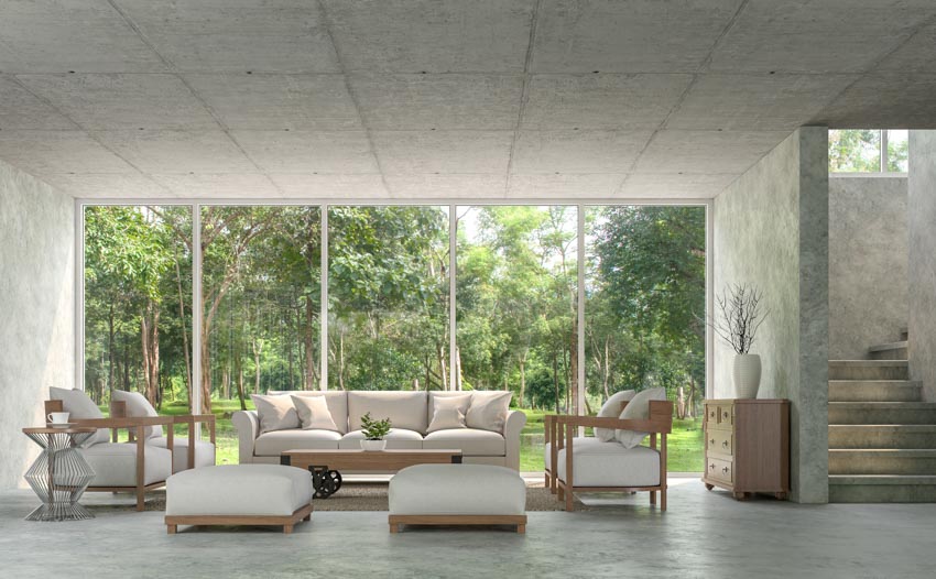 Living room with concrete overlay, ottoman, couch, chairs, and windows