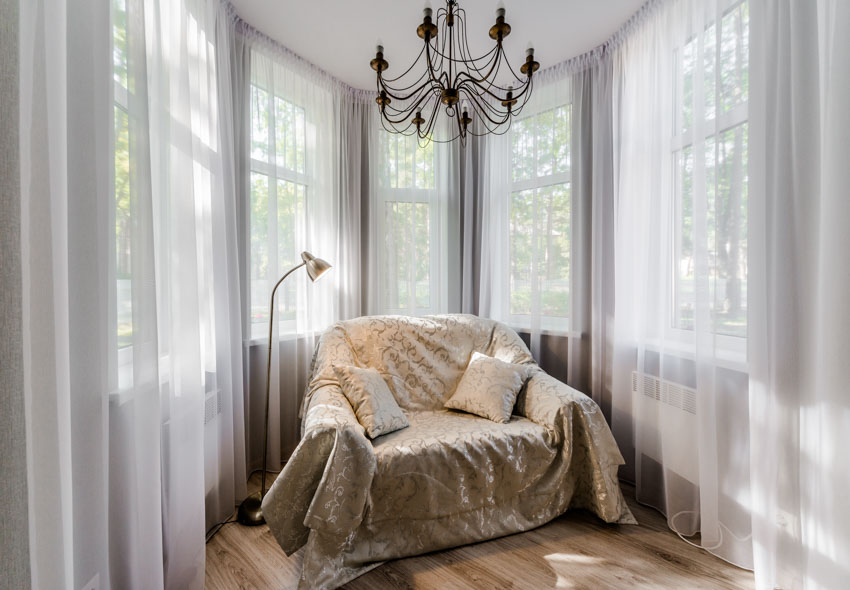 White sofa chair, wrought iron chandeliers and sheer curtains