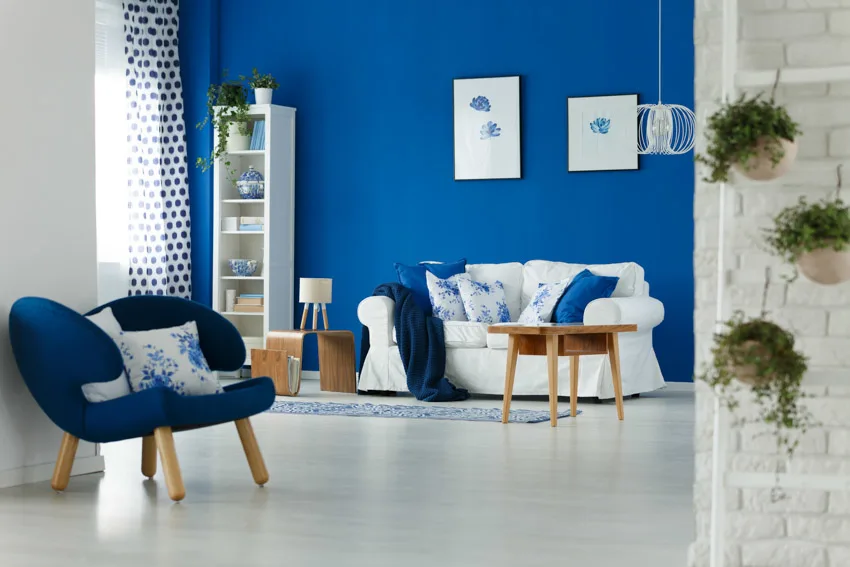 Room with blue accent wall, white couch and blue armchair