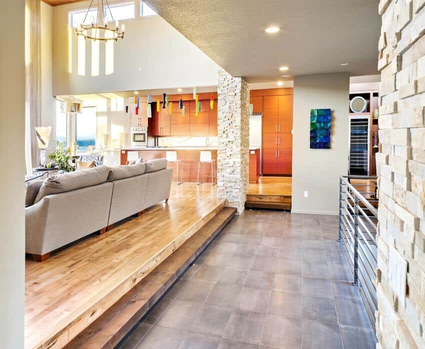 Luxurious living room and hallway with recessed lighting, tile floors, and stone columns