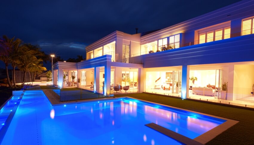 Luxurious white villa at night with a big pool with color changing lights