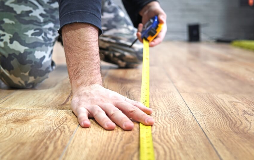 male hands measuring wood flooring