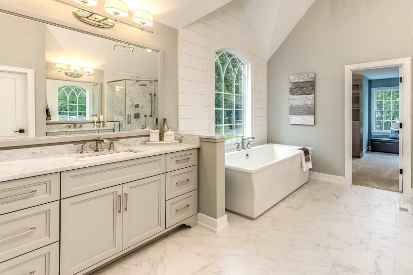 Marble bathroom with freestanding tub, stylish lighting, and under-mounted sink in vanity