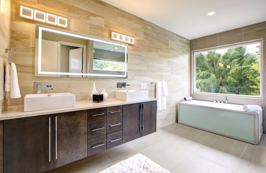 Master bathroom with a dark vanity cabinet, wall mount faucets, and modern tub by the window