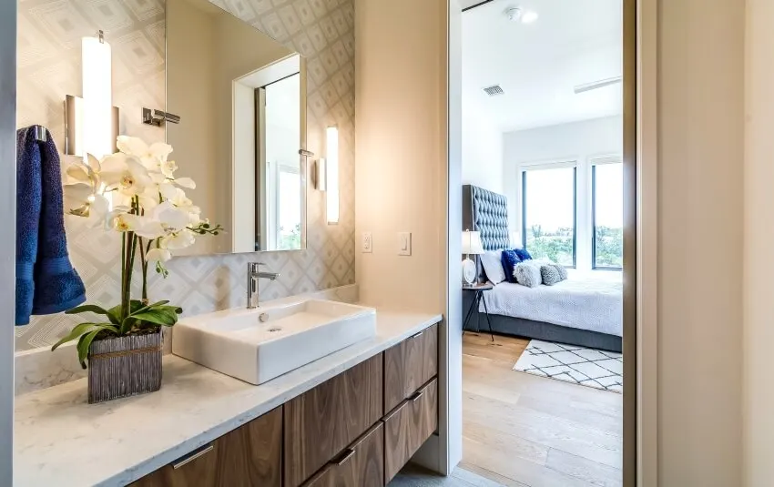 Bathroom with wallpaper, vessel sink on countertop, and wood vanity