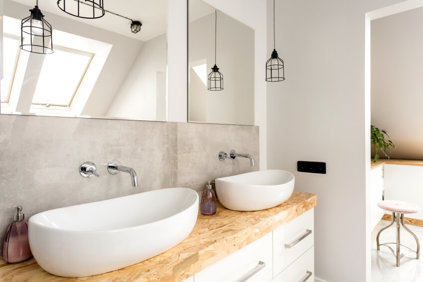 Minimalist bathroom with two vessel sinks on wooden vanity top and pendant lights