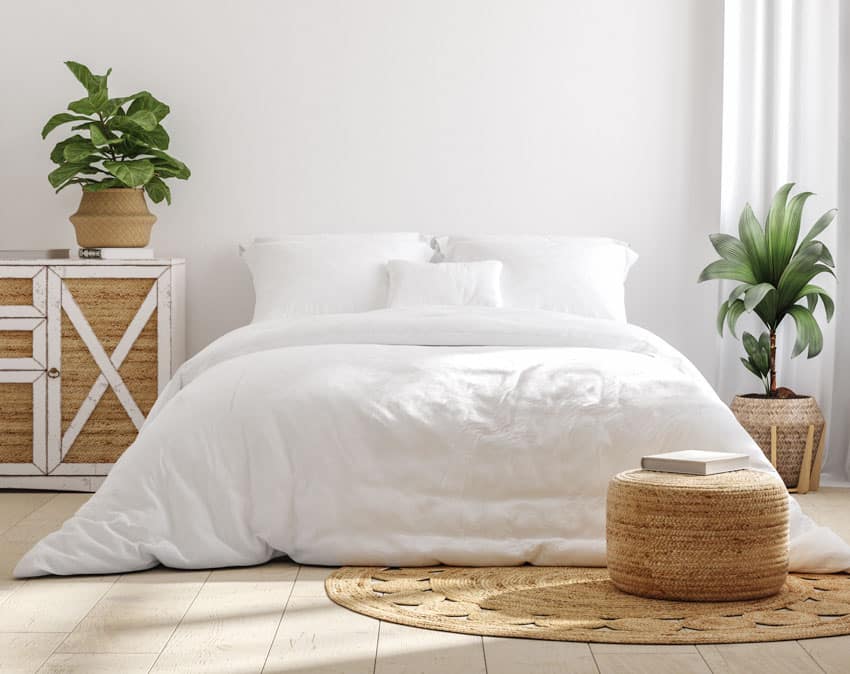 Minimalist bedroom with white comforter, pillows, wood floor, and indoor plants