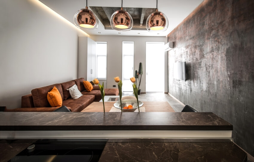 Modern apartment with noir saint laurent marble kitchen countertops, concrete wall, and brown sofa