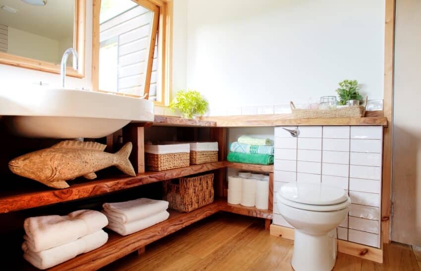 Modern bathroom interior with a toilet against a tiled wall and toiletries on a wooden shelves