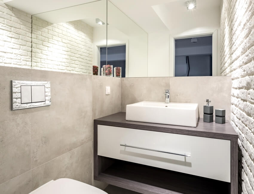 Modern bathroom with brick wall toilet and laminate wood vanity