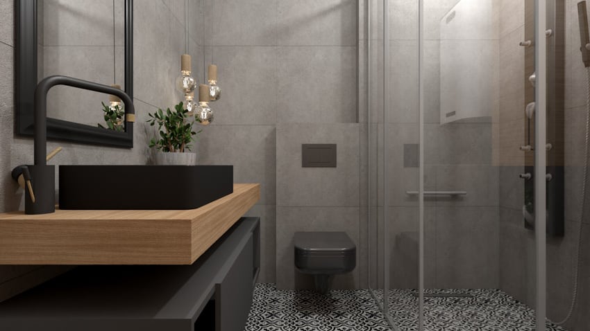 Modern bathroom with butcher block countertop, black toilet, tile flooring, mirror, sink, and shower area