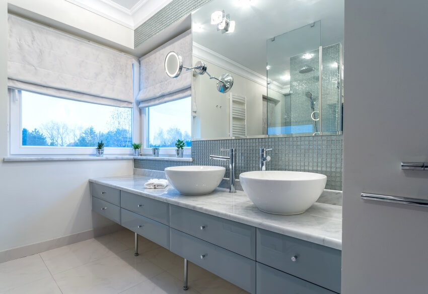 Modern bathroom with two sinks on quartzite vanity countertop, glass tile backsplash, and windows