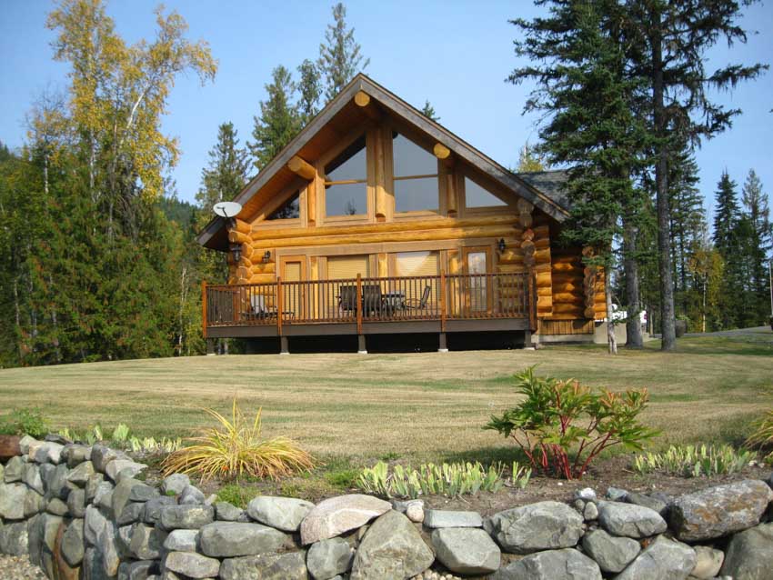 Modern cabin exterior with log siding, windows, and deck