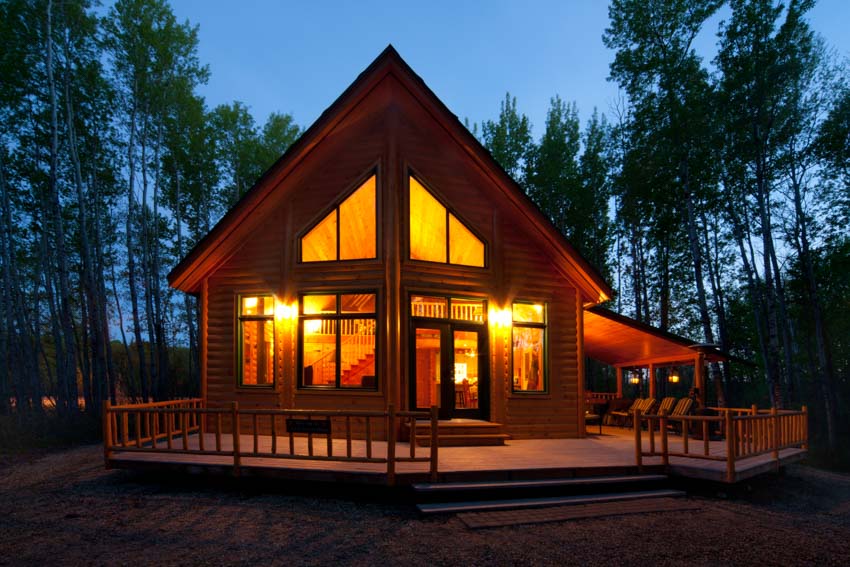 Modern cabin with pitched roof, windows glass, door, and deck