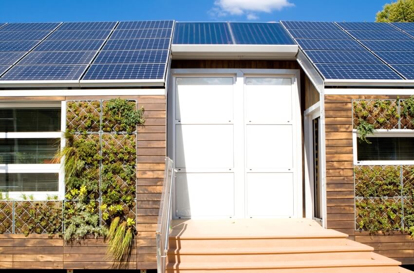 Modern house with roof solar panels and plant on the exterior walls