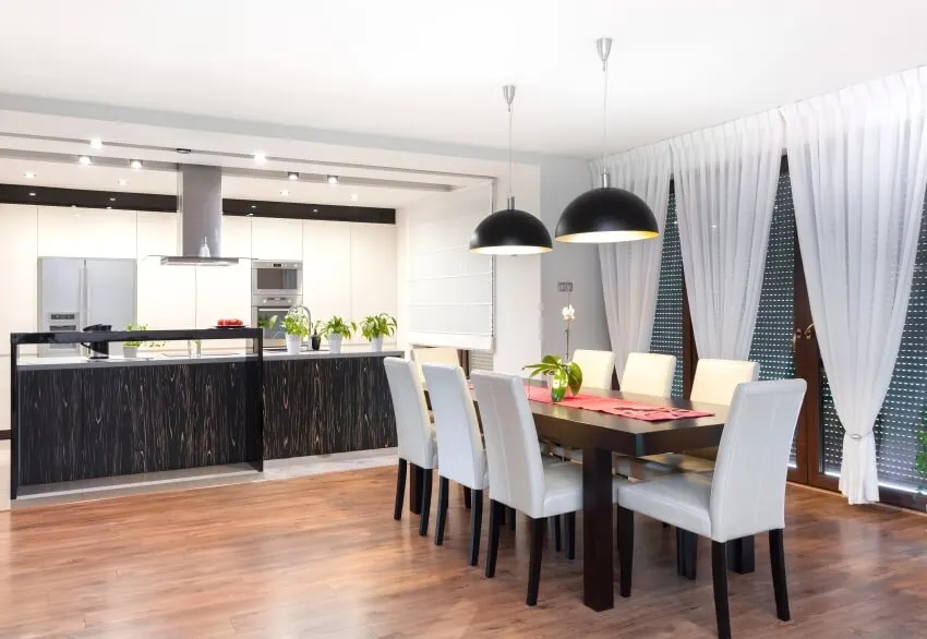 Modern kitchen and dining room with pendant lights, wood floor, and wine cabinet