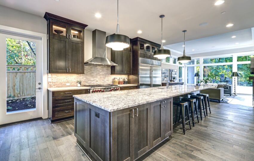 Modern kitchen with brown cabinets, large island with bar stools, and granite countertops