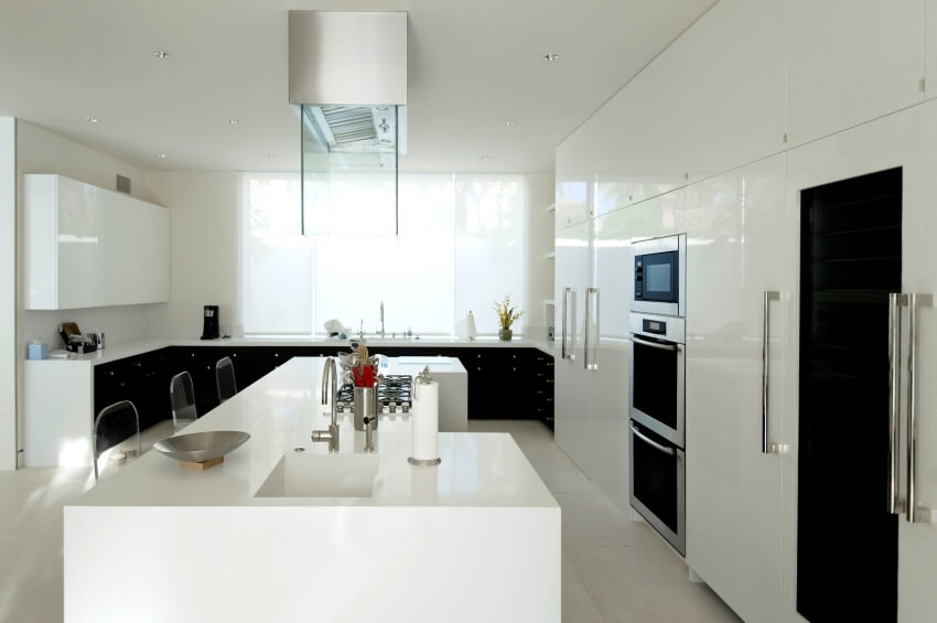 Modern style white kitchen with large island, built-in appliances. and tile floor