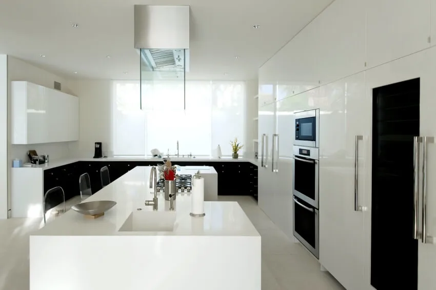 White kitchen with island with sink and white cabinets with chrome handles