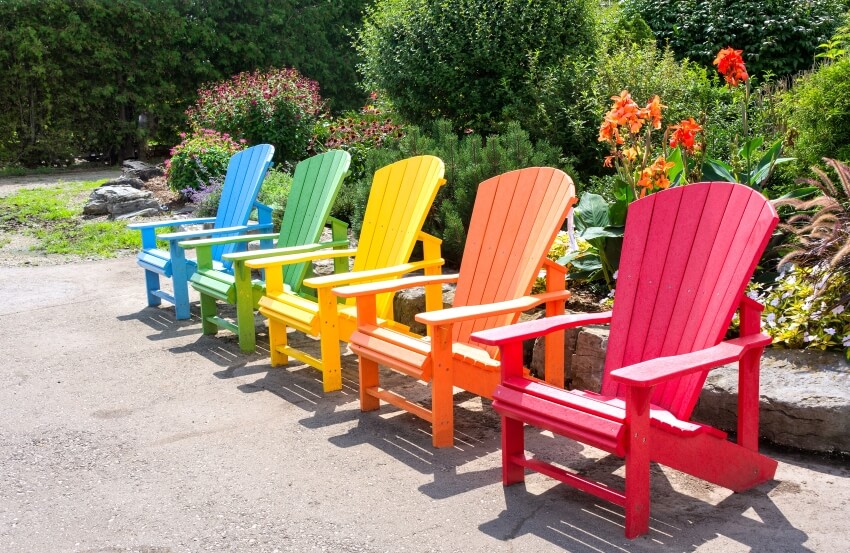 Multicolored and wooden adirondack chairs in a garden
