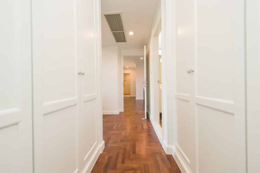 Narrow hallway with wood tile floors, and white doors