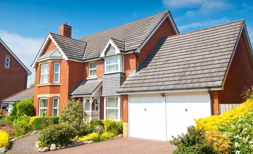 Newly built house with brick facade roof shingles and a beautiful garden