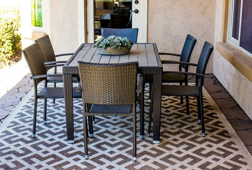 Outdoor patio area with table, chairs, and floor rug