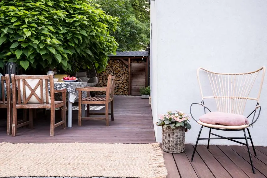 Outdoor patio with table, chairs, wood plank flooring, and outdoor rug