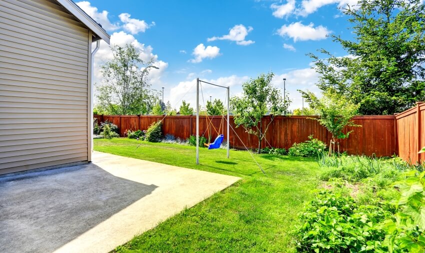 Playground for kids on backyard with lawn and wood fence