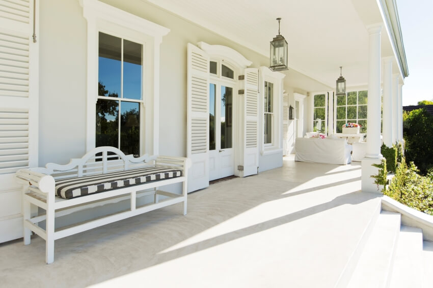 Porch of luxury house with columns, pendant lamps, exterior door shutters, and bench