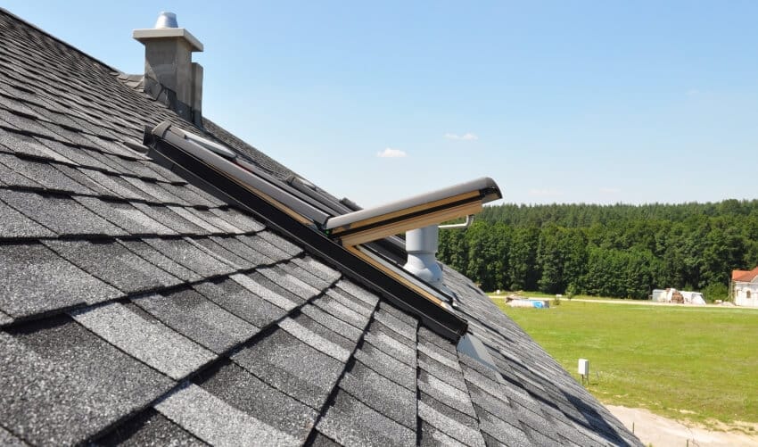 Shingle roof of a house with an open skylight window