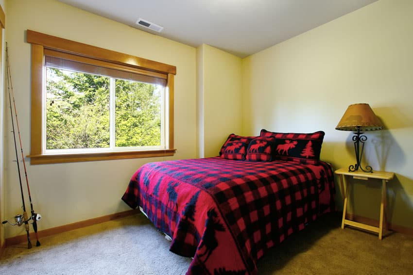 Simple bedroom with black and red comforter, nightstand, lamp, and window