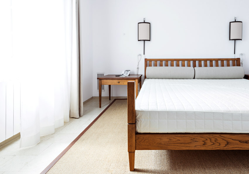 Simple bedroom with latex mattress, wood frame, nightstand, lamp, and window curtains