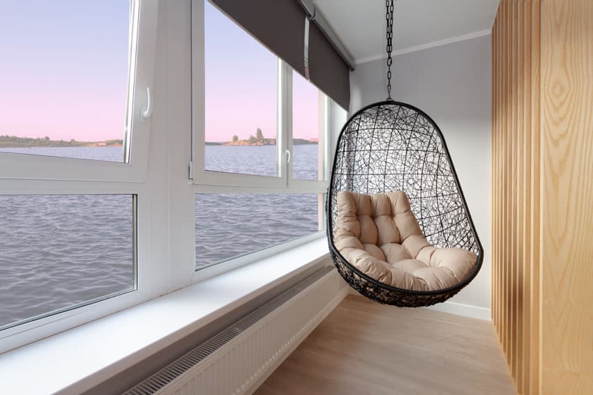 Simple room with windows, wood divider, and hanging egg chair design