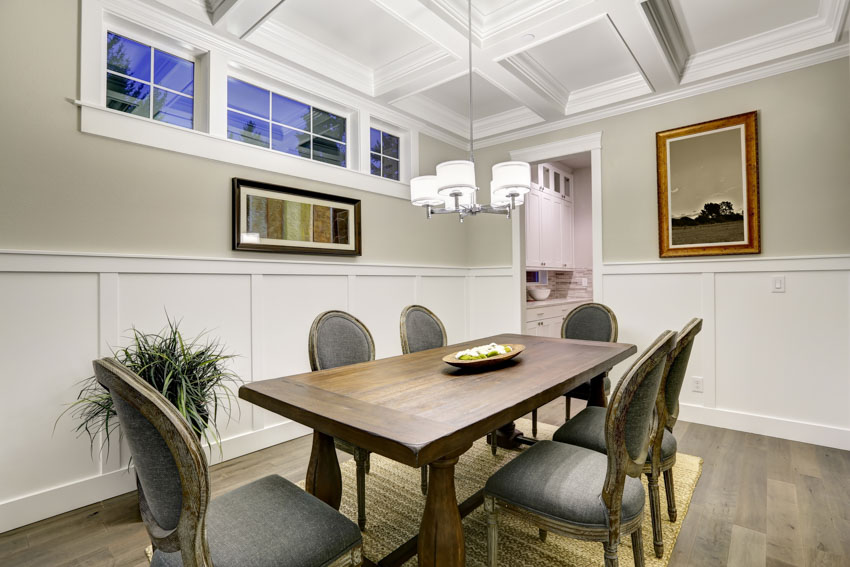 Small dining room with wood table, cushioned chairs, and wainscoting